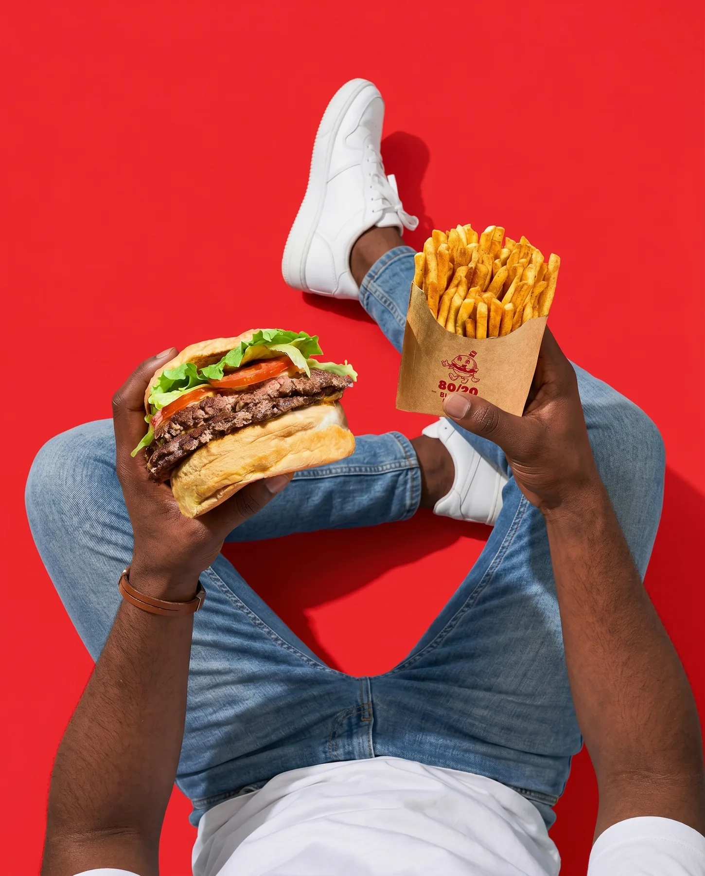 A burger and fries held up from a red floor