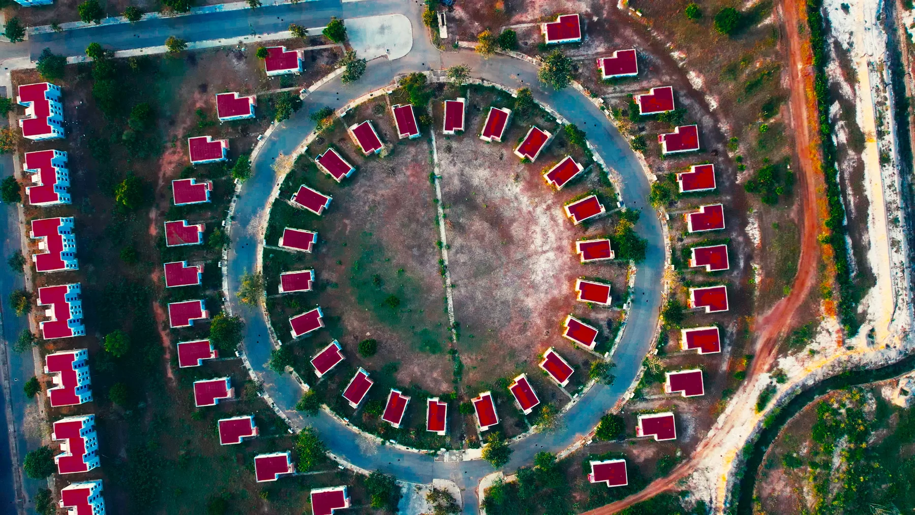 Drone photograph looking straight down on a ring of homes around a central green