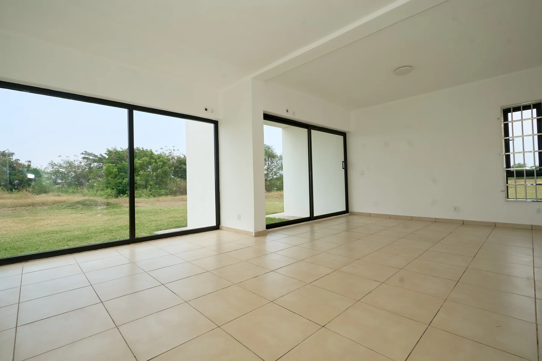 Photograph of an empty living room with tall windows onto the estate